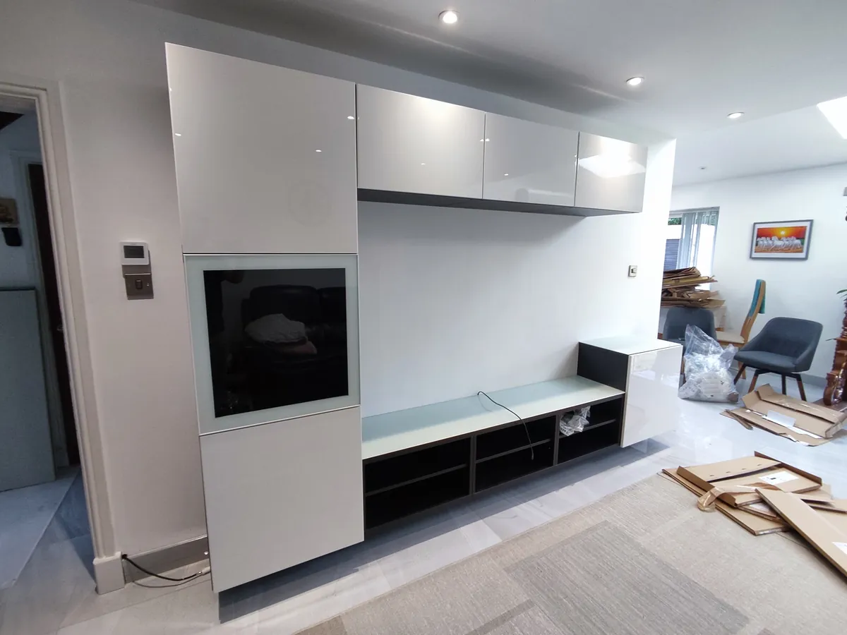 Built-in gloss white TV wall with a recessed screen niche and overhead cabinets