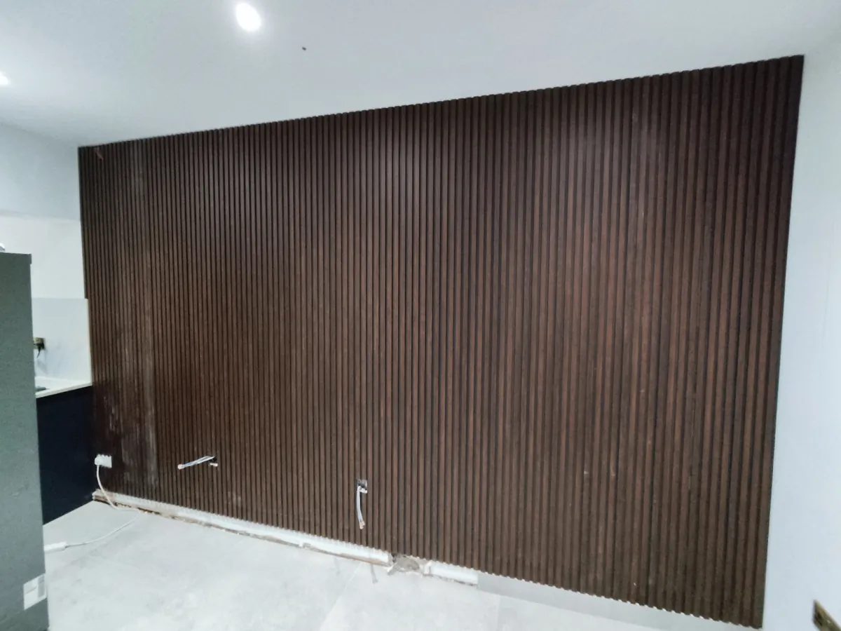 Full-wall dark walnut slat panelling in an open-plan room