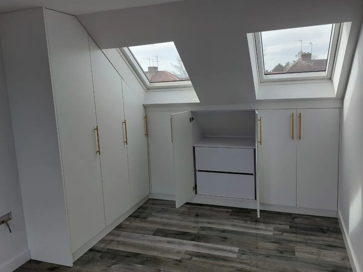 Bespoke loft fitted wardrobes under two Velux windows, with an eaves cupboard open to show the drawers inside
