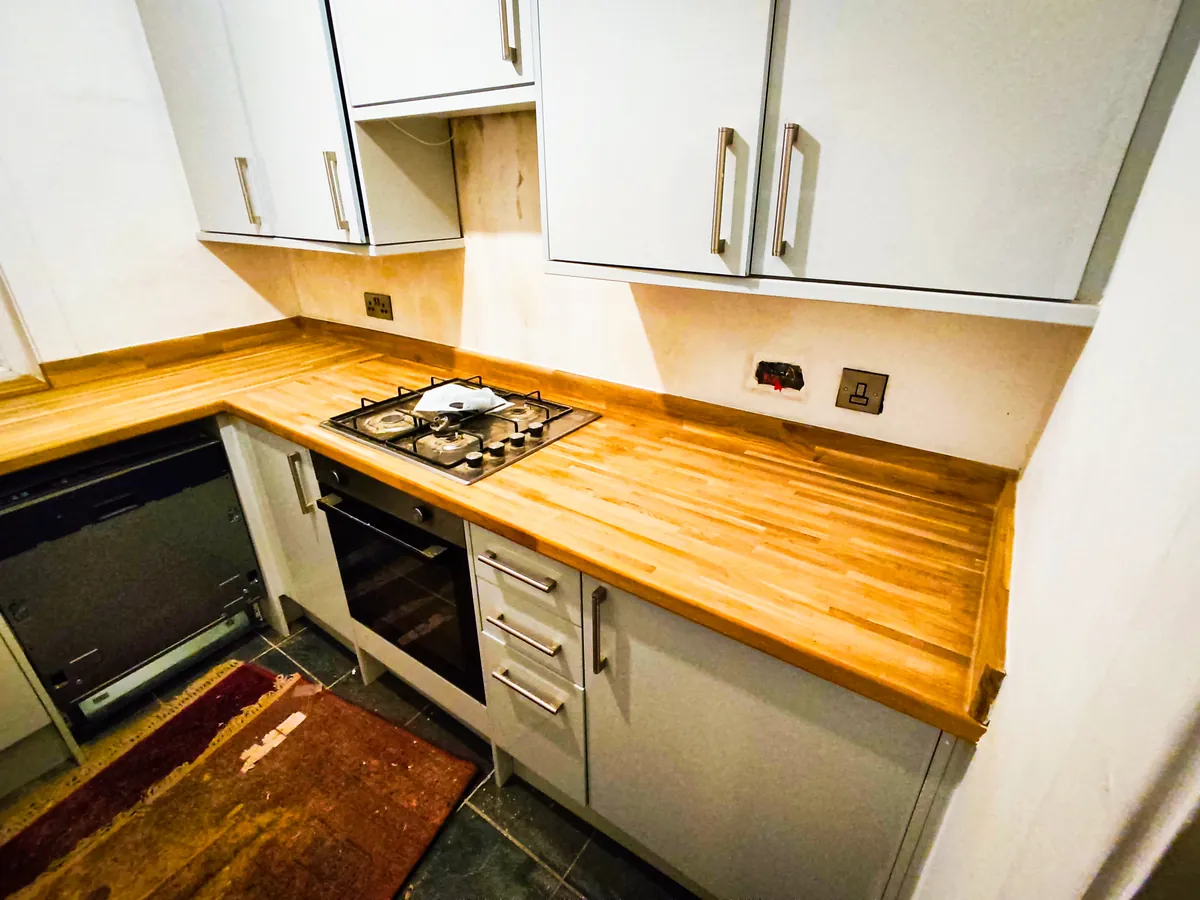 Oak worktop with a gas hob and built-in oven in a fitted kitchen corner