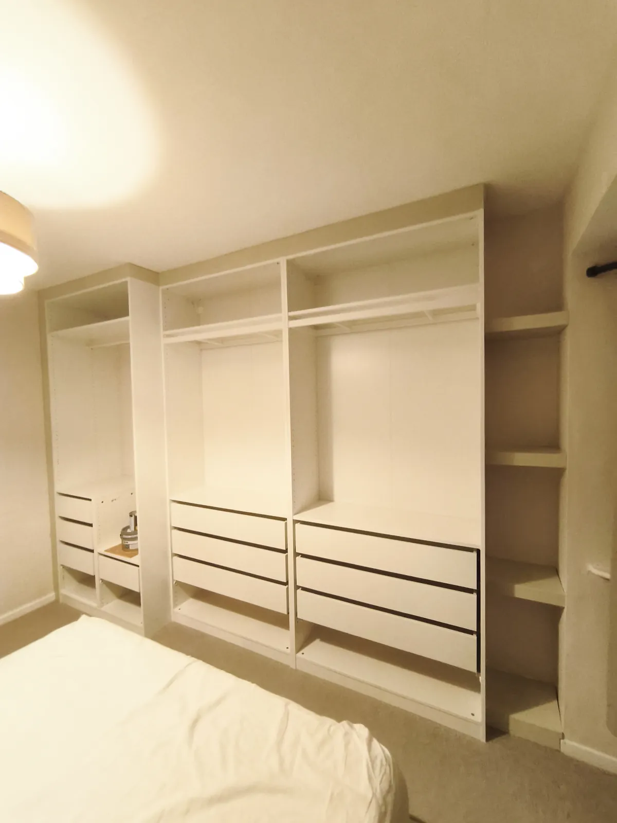 All the IKEA PAX frames fixed to the wall with filler boards at the sides and open shelves at the end, ready for doors