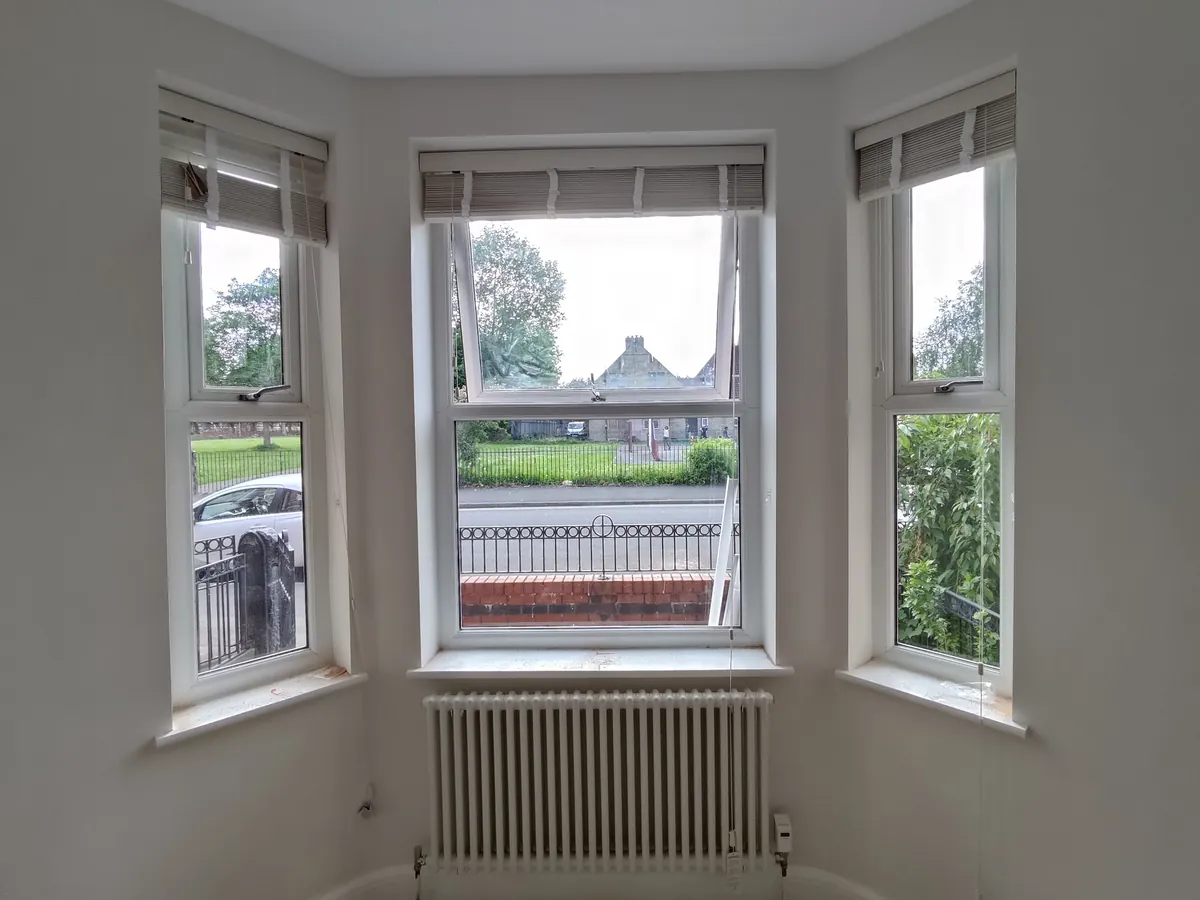 Roman blinds fitted across a three-part bay window above a radiator